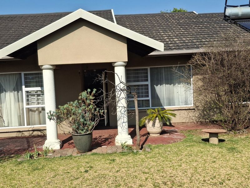 Front elevation of a single-story house featuring a covered entrance porch with decorative columns, tiled roof, and integrated solar water heating system.