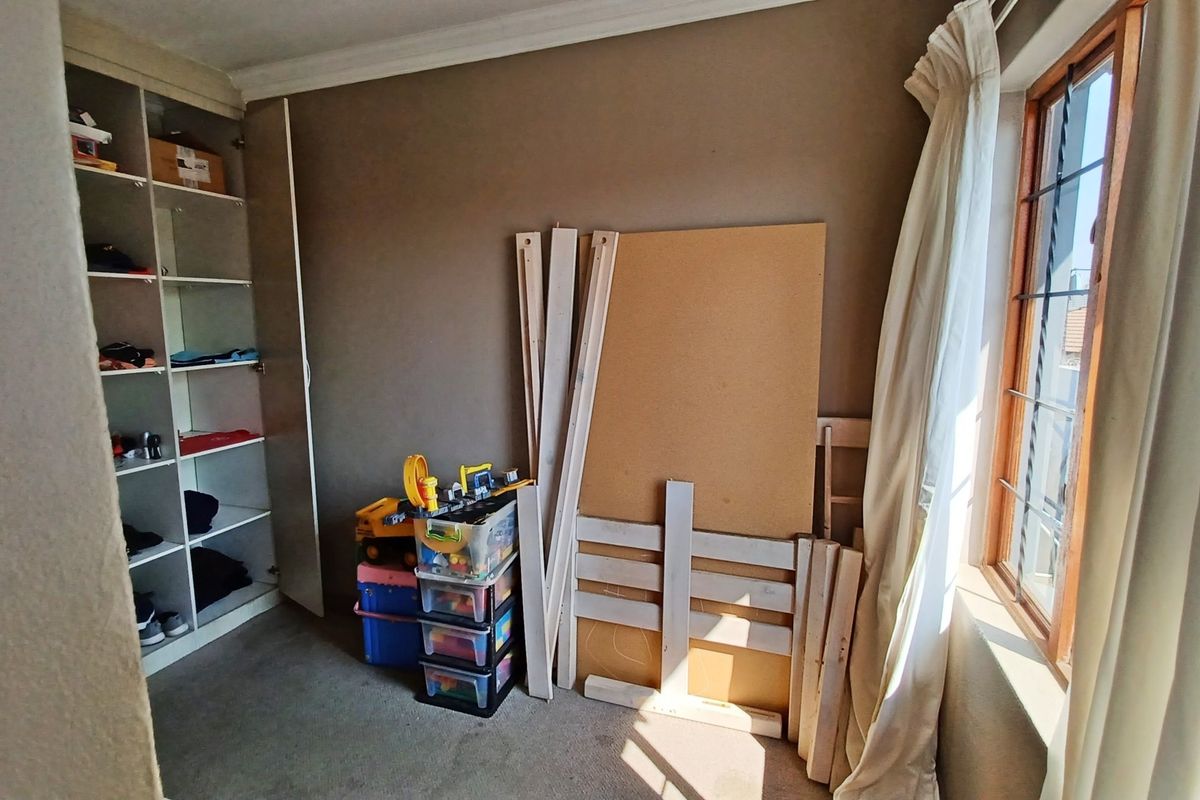 A bedroom featuring built-in cupboards, carpeted flooring, and a timber window frame, offering a functional space ready for personalization.