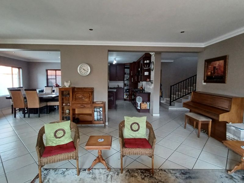 Spacious open-plan living area featuring tiled floors, recessed lighting, and a seamless flow between the dining space, kitchen, and staircase.