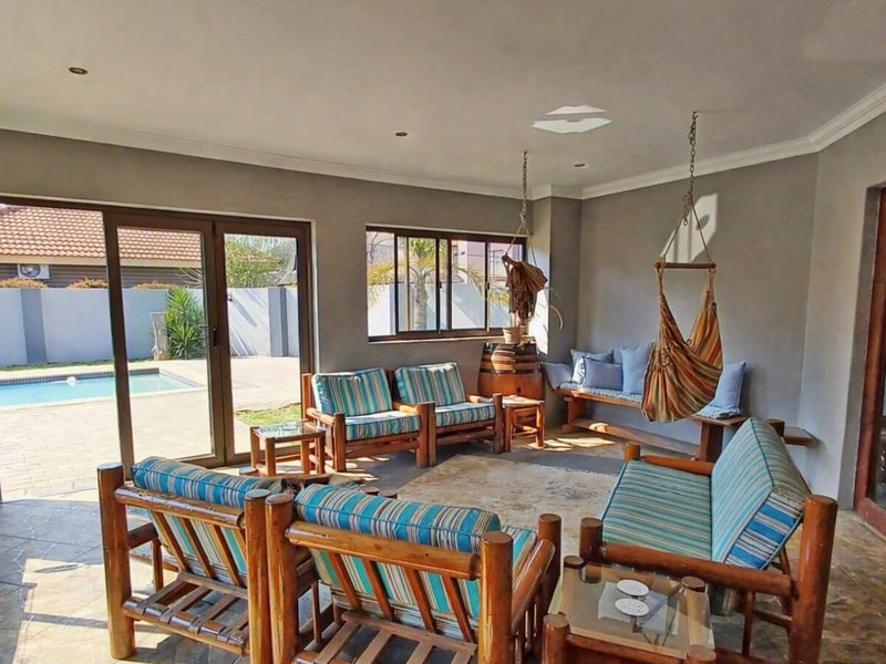 A covered patio area featuring tiled flooring, recessed lighting, and large sliding glass doors providing direct access to the outdoor pool area.