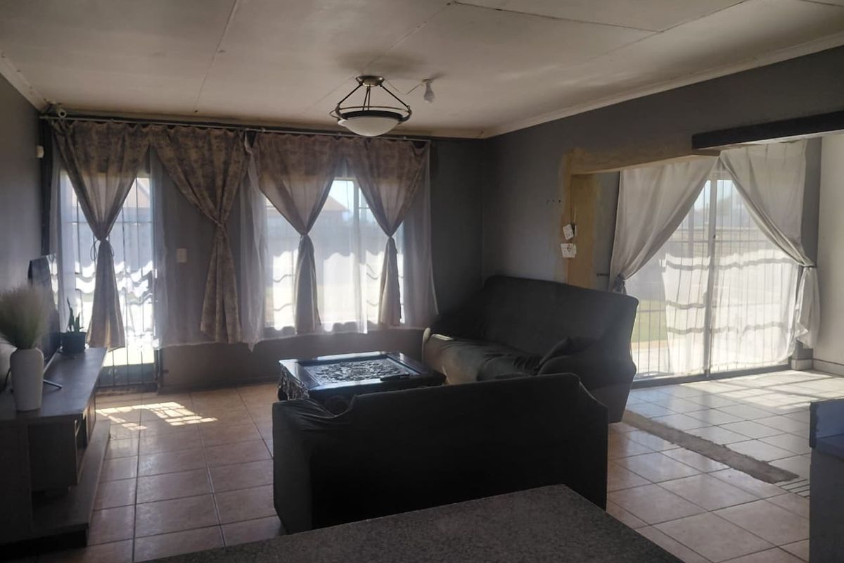 Spacious living area featuring tiled flooring and multiple sliding glass doors providing natural light, requiring some ceiling and wall finish repairs.