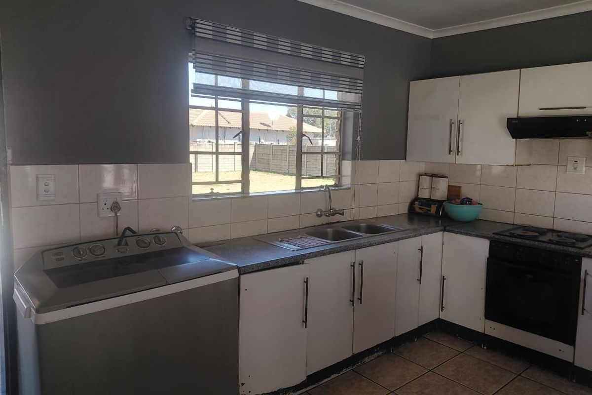 Functional kitchen featuring built-in cabinetry, double basin sink, integrated oven and hob, tiled backsplash, and tiled flooring.