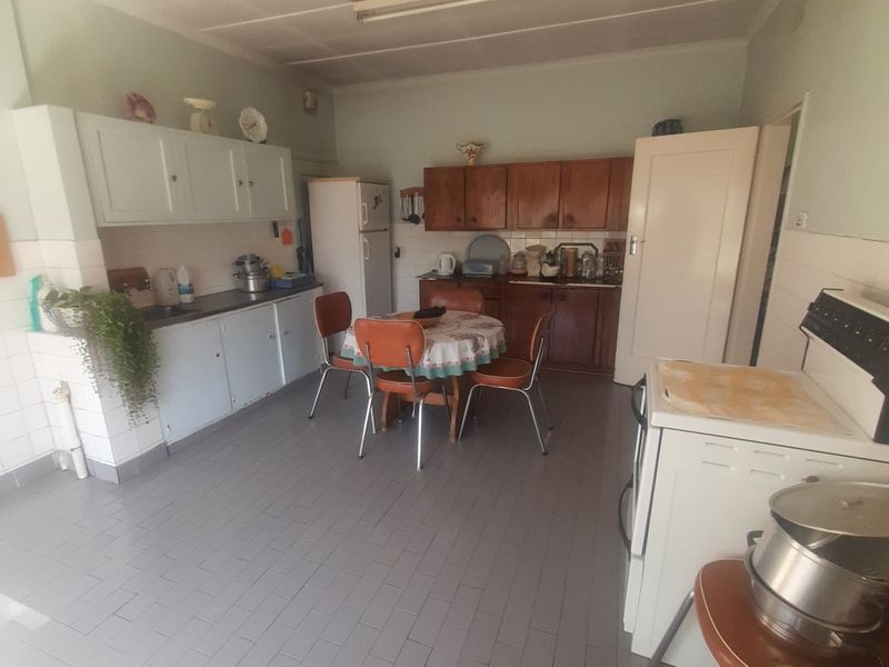 A dated kitchen featuring original cabinetry, tiled flooring, and a freestanding stove, offering significant potential for a modern renovation.
