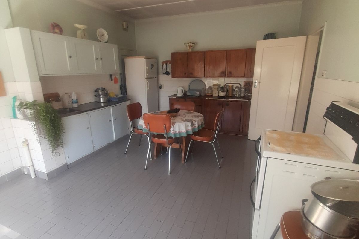 A dated kitchen featuring original cabinetry, tiled flooring, and a freestanding stove, offering significant potential for a modern renovation.