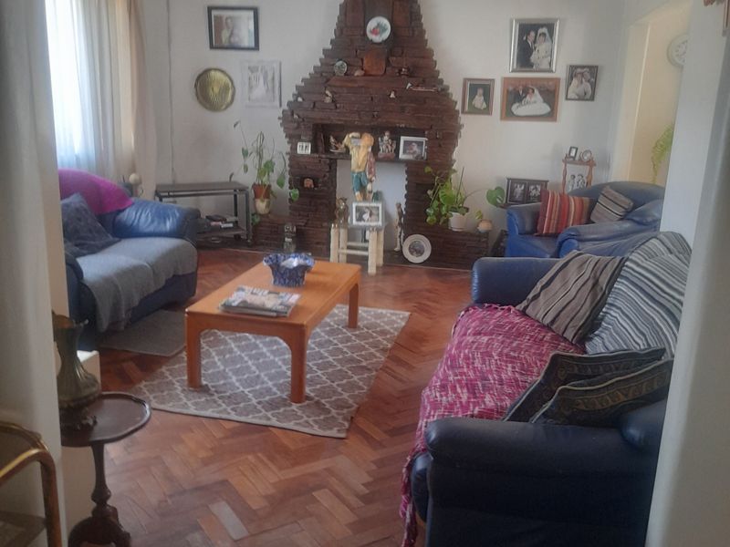 A traditional living room featuring a prominent brick fireplace and classic herringbone parquet flooring, offering a warm and character-filled space.