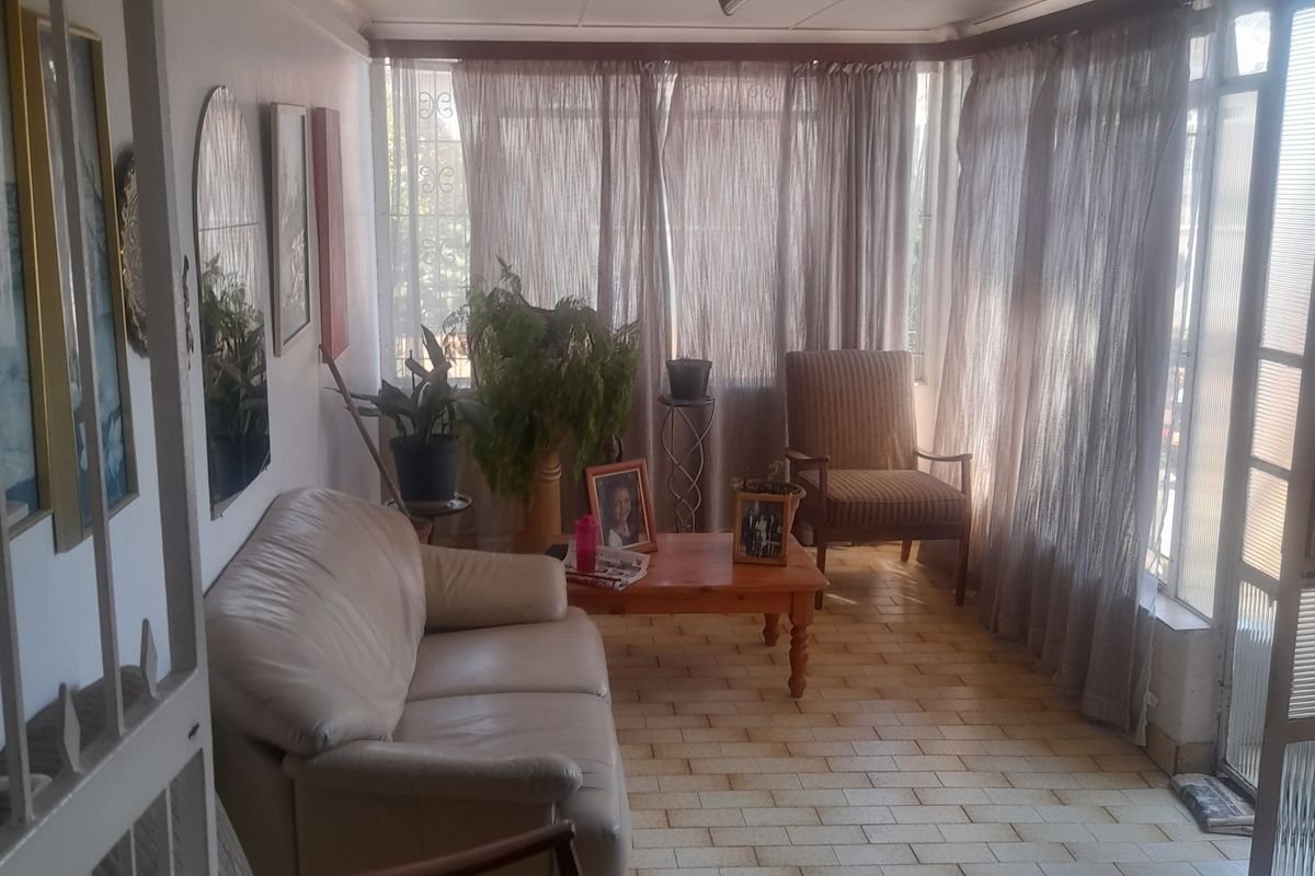 A sunlit living area featuring tiled flooring and large windows, providing a bright and comfortable space for relaxation.