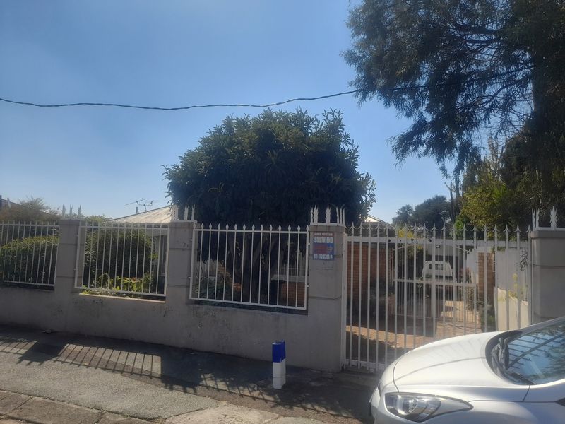 Front exterior view of the property featuring a perimeter wall with metal security fencing and a gated driveway entrance.