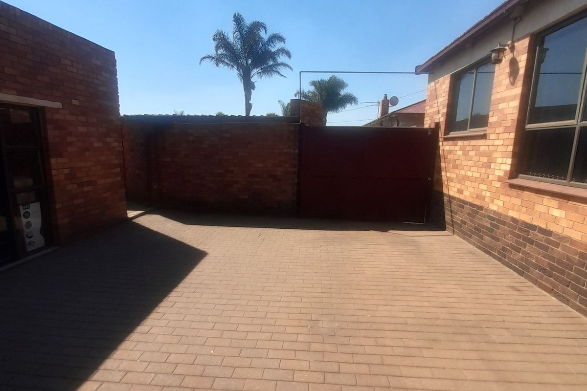 A paved rear courtyard area featuring face brick walls and a secure metal gate, providing a private outdoor space.