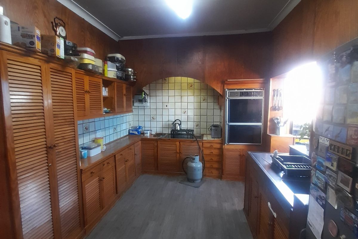 A dated kitchen featuring extensive wooden cabinetry, a built-in double oven, and tiled splashbacks, offering significant potential for a modern renovation.