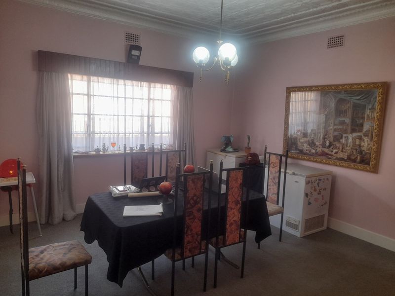 A dining room featuring decorative ceiling cornicing, a central chandelier, and large windows, providing a functional space for meals.
