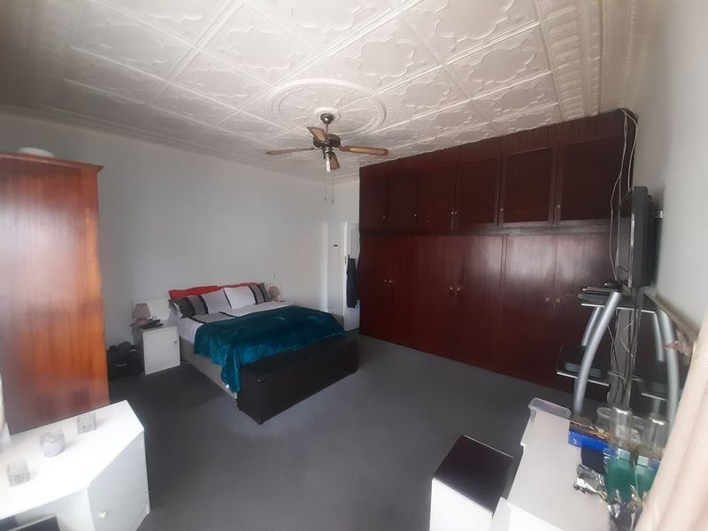 Spacious bedroom featuring extensive built-in wooden cabinetry, a ceiling fan, and decorative ceiling detailing.