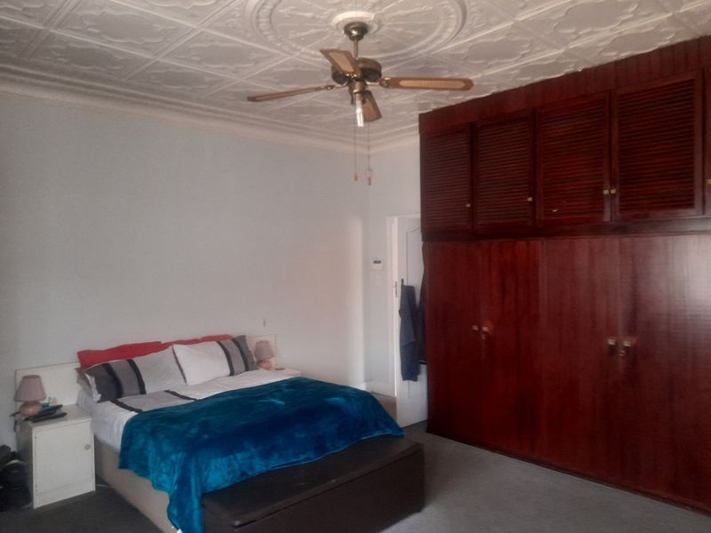 A bedroom featuring decorative ceiling tiles, a ceiling fan, and extensive built-in wooden cabinetry providing ample storage space.