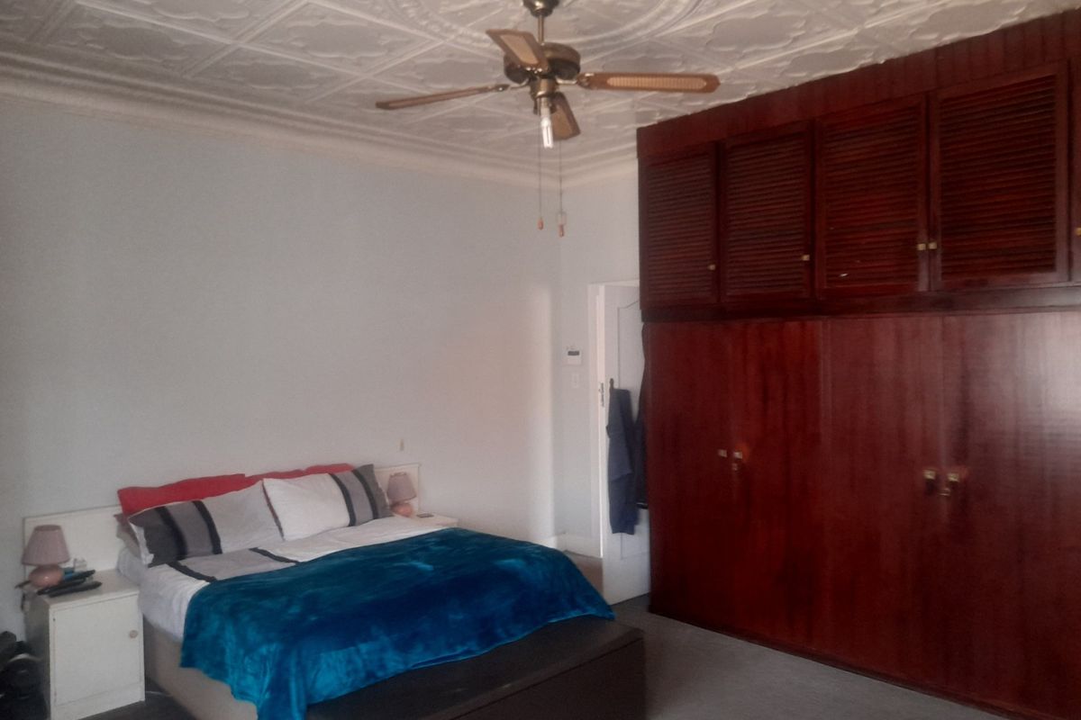 A bedroom featuring decorative ceiling tiles, a ceiling fan, and extensive built-in wooden cabinetry providing ample storage space.