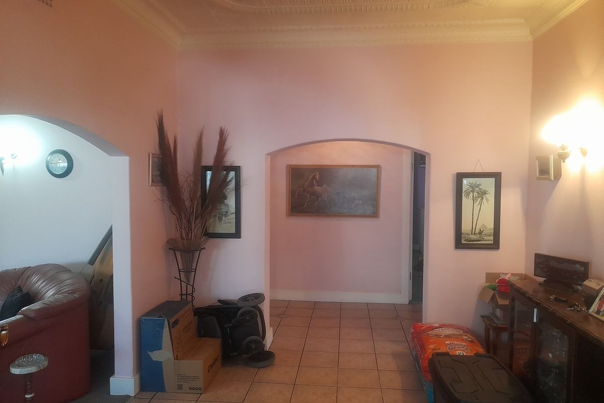 A living area featuring an ornate ceiling, tiled flooring, and arched doorways leading to adjacent spaces.
