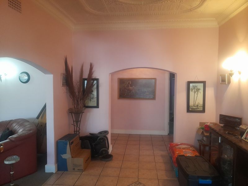 A living area featuring an ornate ceiling, tiled flooring, and arched doorways leading to adjacent spaces.