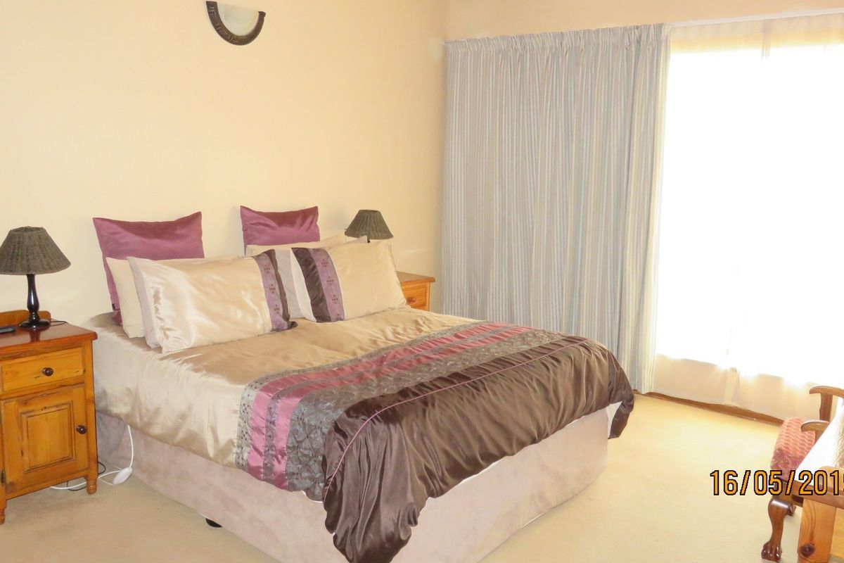 A standard bedroom featuring neutral wall finishes, carpeted flooring, and a sliding door providing access to the exterior.