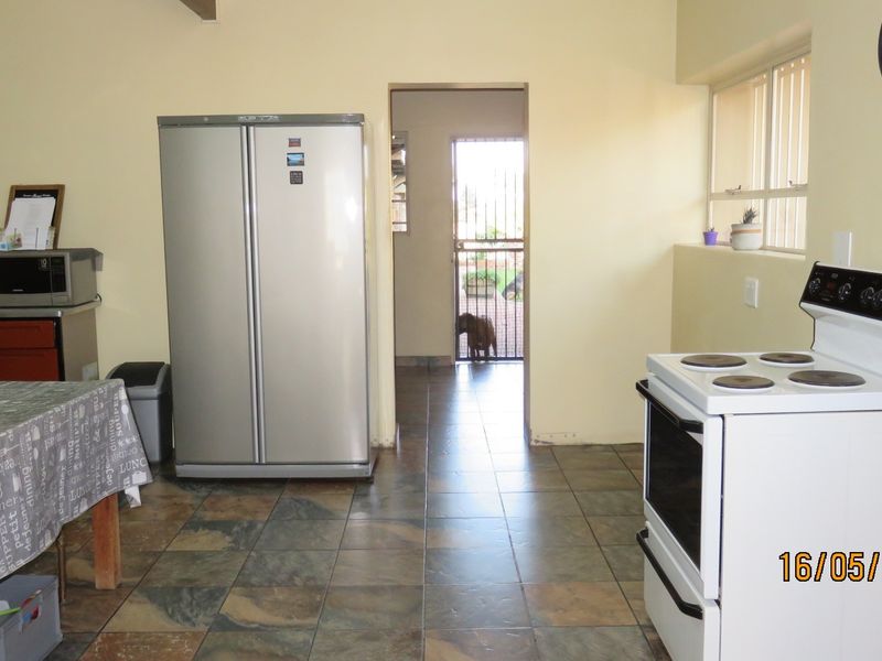 A functional kitchen area featuring tiled flooring, built-in cabinetry, and a freestanding stove, with direct access to an exterior security gate.