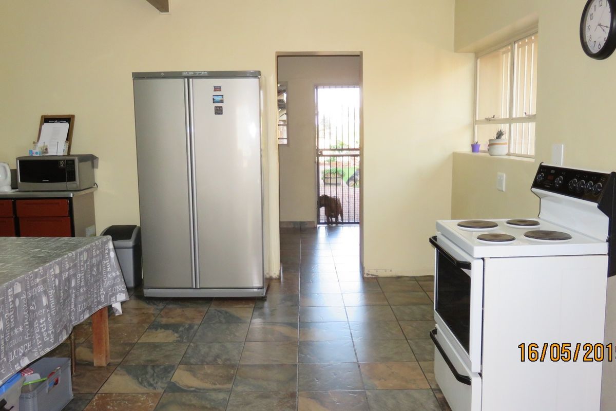 A functional kitchen area featuring tiled flooring, built-in cabinetry, and a freestanding stove, with direct access to an exterior security gate.