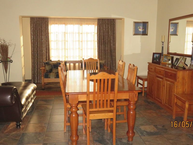 A dining room featuring slate tile flooring and a large window with curtains, providing a functional space for family meals.
