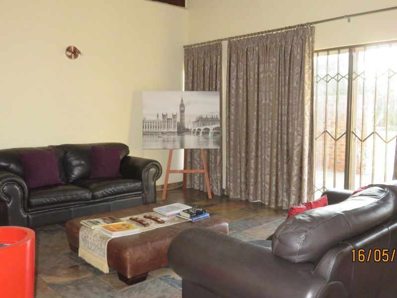 A living room featuring tiled flooring and a sliding glass door with security gate, providing access to the outdoor area.