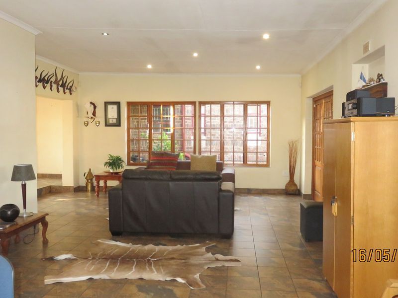 Spacious living room featuring tiled flooring, recessed downlighting, and large wooden-framed windows allowing natural light into the area.