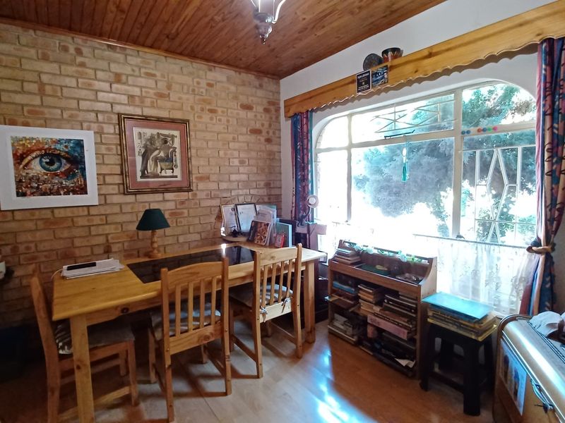 A living area featuring an exposed brick feature wall, timber ceiling, and a large arched window providing natural light.