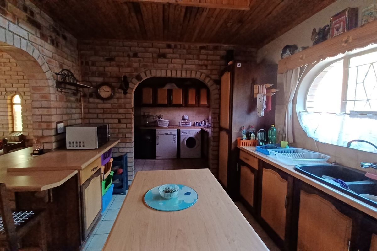A rustic kitchen featuring exposed brick walls, timber ceiling, arched architectural details, and built-in cabinetry with a double basin sink.