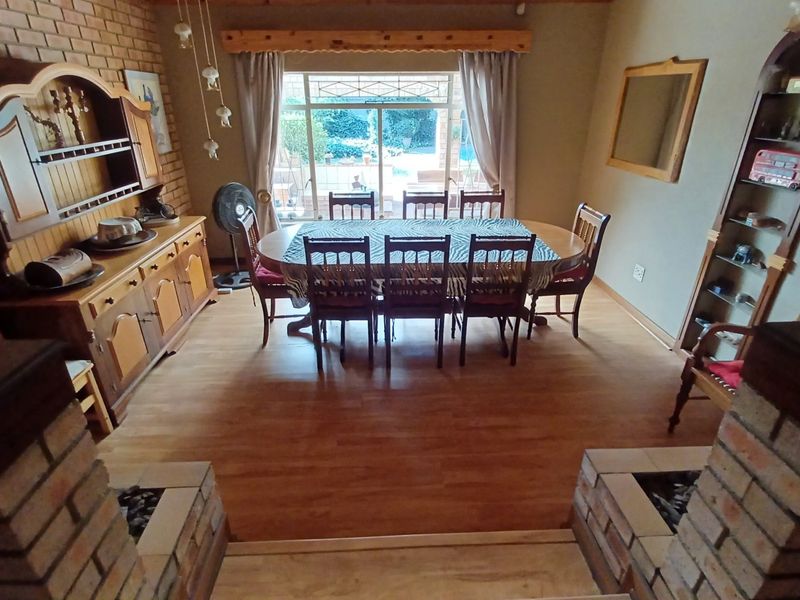 Dining room featuring exposed brick walls, laminate flooring, and a large sliding glass door providing natural light and garden views.