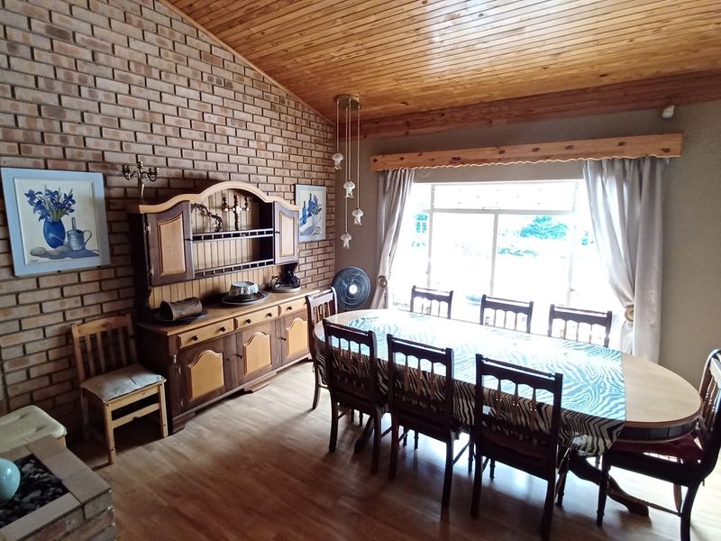 Dining room featuring an exposed brick feature wall, timber ceiling, and large window providing natural light.