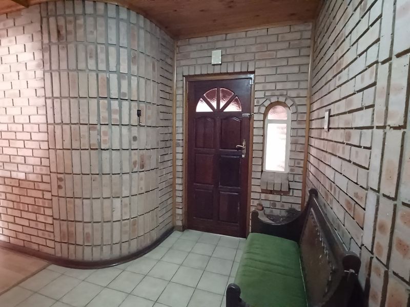 Entrance foyer featuring distinctive exposed brick walls, a curved architectural feature, timber ceiling, and tiled flooring leading to a solid timber front door.