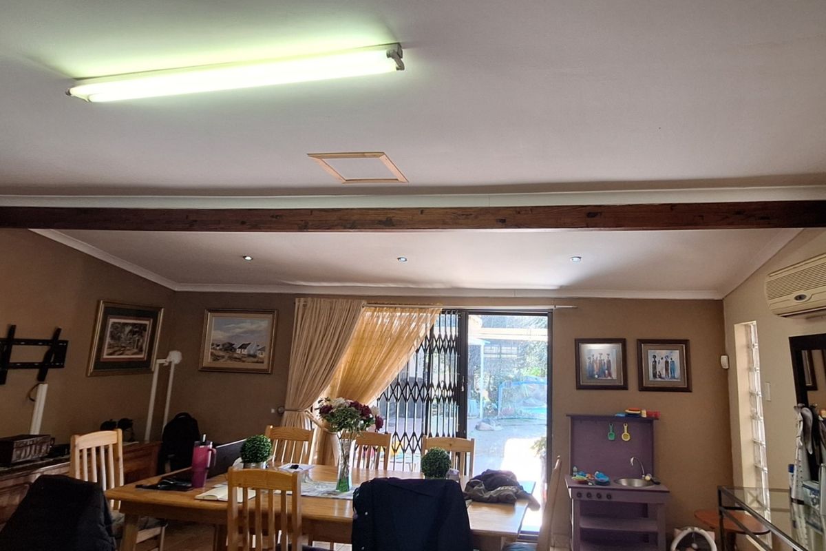 Spacious living area featuring an exposed timber ceiling beam, recessed lighting, and a sliding glass door providing access to the outdoor area.