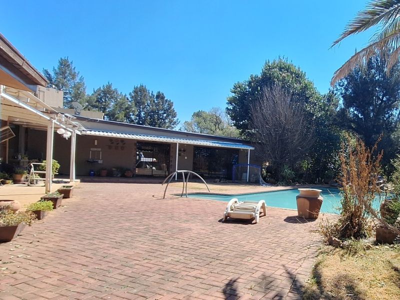 Outdoor pool area featuring a brick-paved patio, covered veranda, and direct access to the main dwelling through sliding glass doors.