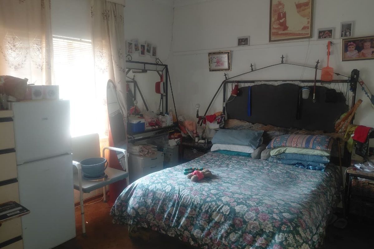 A bedroom featuring a window with natural light and a traditional picture rail, requiring cosmetic updates to the flooring and wall finishes.