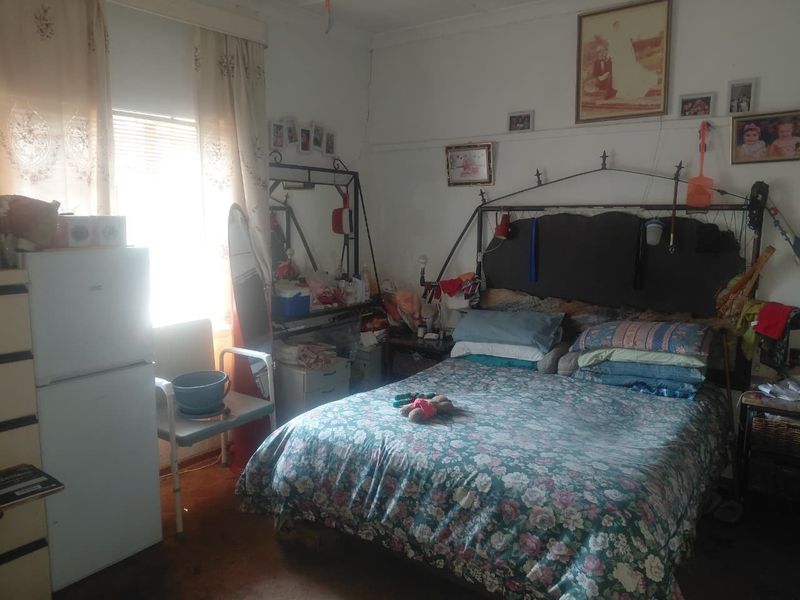 A bedroom featuring a window with natural light and a traditional picture rail, requiring cosmetic updates to the flooring and wall finishes.