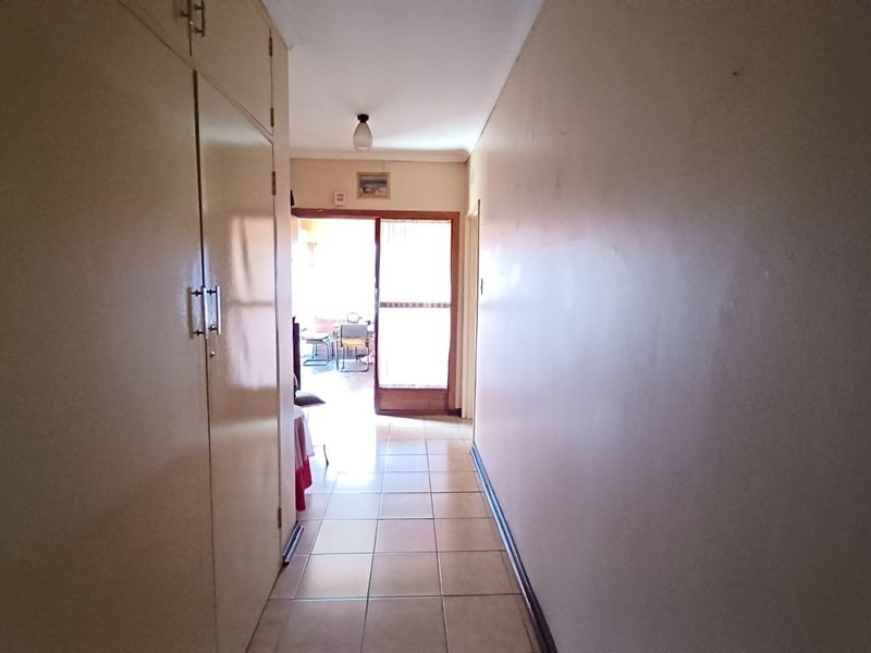A functional hallway featuring built-in storage cupboards and tiled flooring, leading towards an exterior doorway.