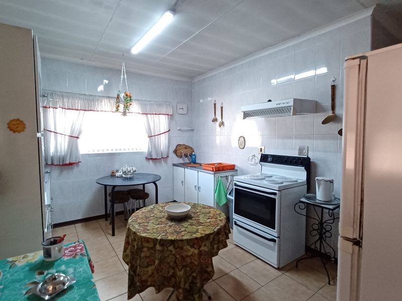 A functional kitchen featuring tiled walls, built-in cabinetry, and a freestanding stove, offering a dated aesthetic with potential for modern renovation.