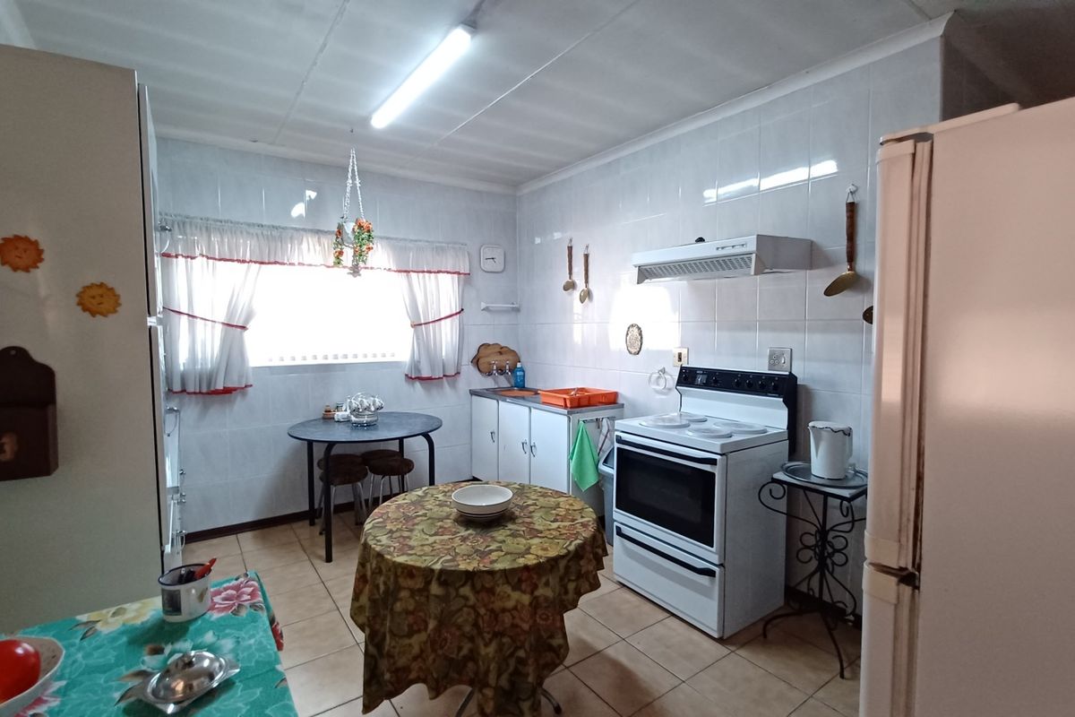 A functional kitchen featuring tiled walls, built-in cabinetry, and a freestanding stove, offering a dated aesthetic with potential for modern renovation.