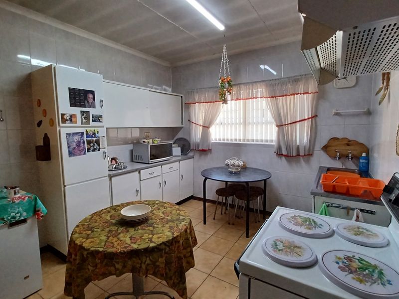 A functional kitchen featuring tiled walls, tiled flooring, built-in cabinetry, and an extractor fan, offering a practical layout for daily meal preparation.