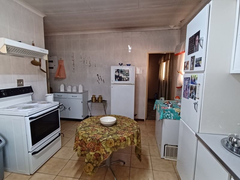 A functional kitchen featuring tiled walls and flooring, built-in cabinetry, and a freestanding stove with an overhead extractor fan.