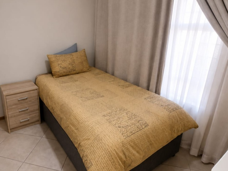 A compact bedroom featuring tiled flooring and a built-in cupboard, offering a functional and well-maintained living space.