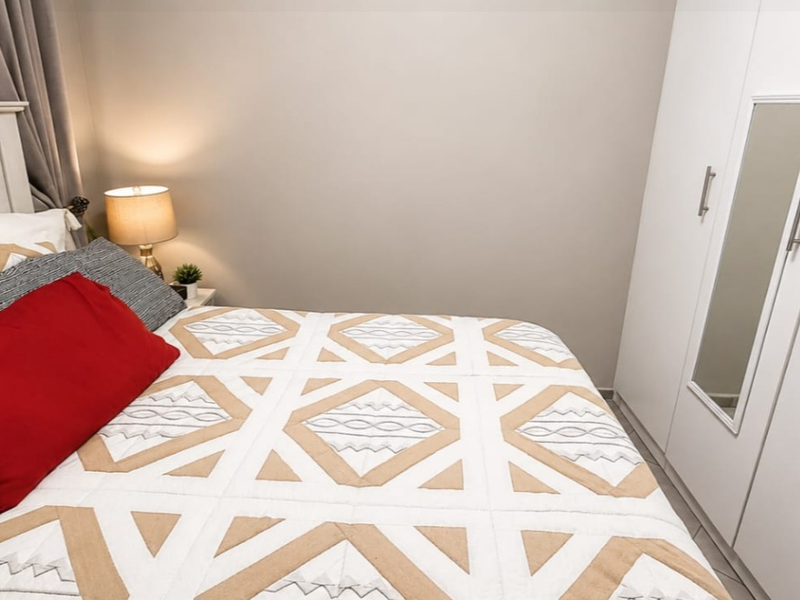 A well-maintained bedroom featuring a built-in wardrobe with a mirrored panel, providing efficient storage and a clean, neutral aesthetic.