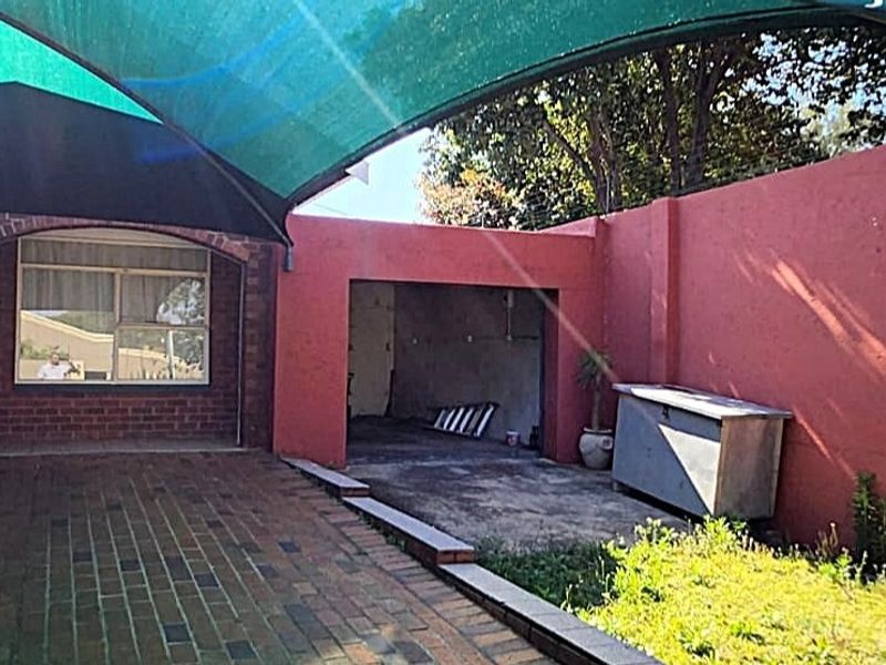 Outdoor patio area featuring brick paving, a shade sail structure, and a masonry boundary wall, offering potential for a refreshed entertainment space.