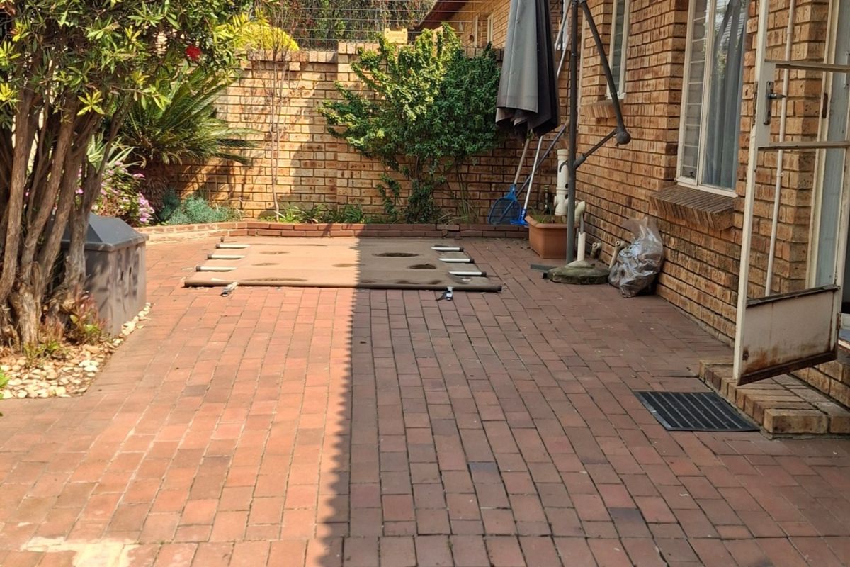 A private rear courtyard featuring brick paving, facebrick walls, and a secure entrance, offering a functional outdoor space for the townhouse.