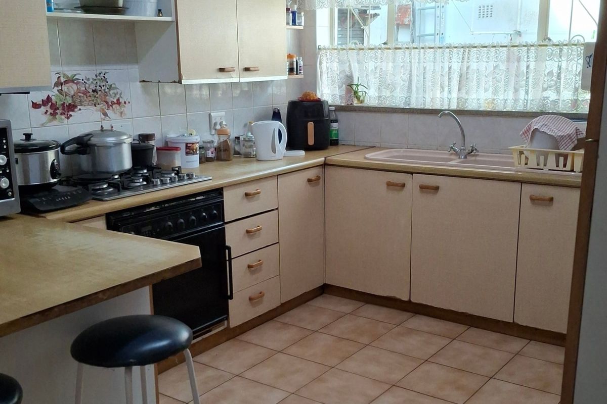 A functional kitchen featuring built-in cabinetry, laminate countertops, a gas hob, oven, and double sink with tiled flooring and backsplash.