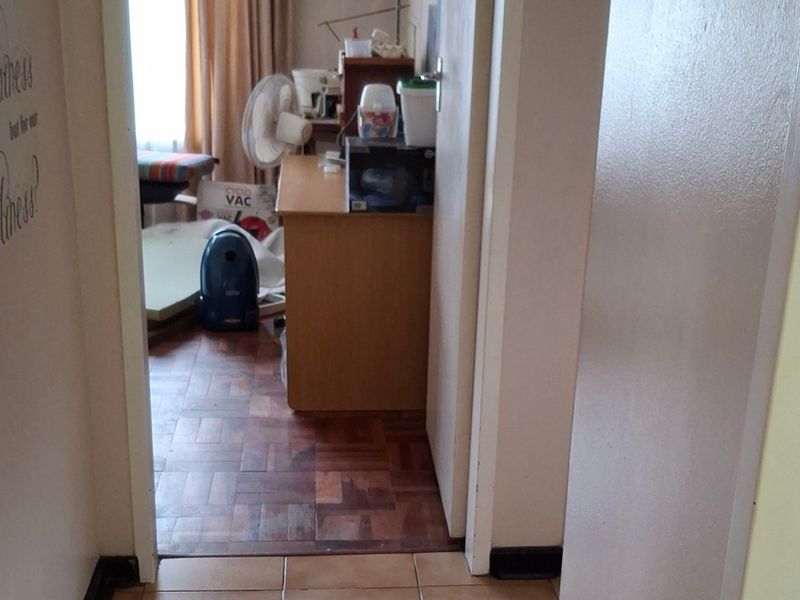 A narrow hallway transition area featuring a mix of parquet and tiled flooring, connecting two interior spaces.