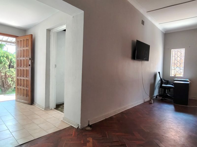 Living area featuring traditional parquet flooring, a tiled entryway, and direct access to the exterior through a timber door with security gate.