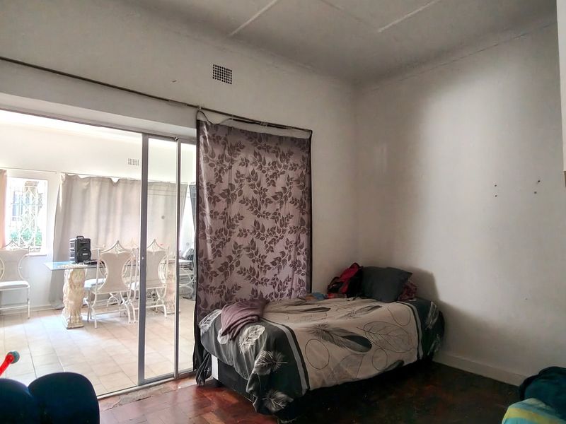 Bedroom featuring parquet flooring and a sliding glass door providing access to an adjacent sunroom or patio area.