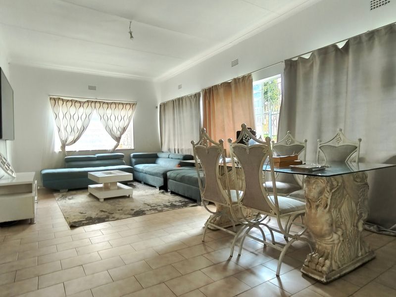 Spacious open-plan living and dining area featuring neutral tiled flooring and large windows, offering a versatile layout for family living.