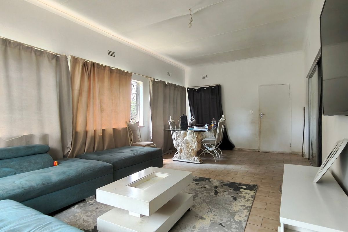 Spacious living area featuring tiled flooring and large windows, offering a blank canvas for renovation and modern interior design updates.