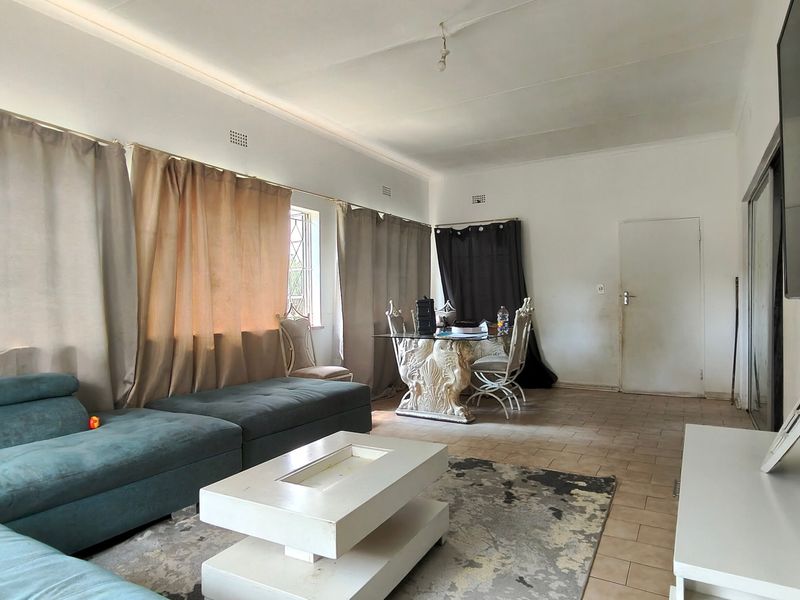 Spacious living area featuring tiled flooring and large windows, offering a blank canvas for renovation and modern interior design updates.
